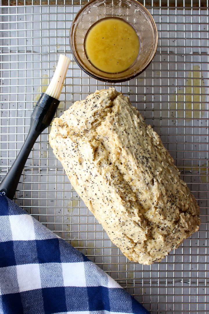 beer bread loaf on a rack with honey butter and a brush ready to be glazed