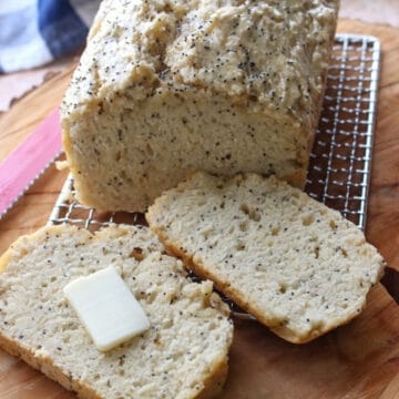 loaf of beer bread with 2 slices cut off. One slice with butter pat in middle