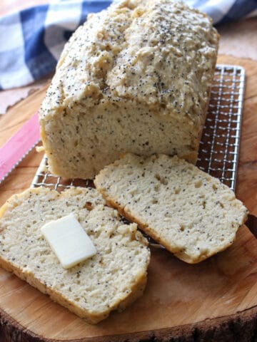 loaf of beer bread with 2 slices cut off. One slice with butter pat in middle