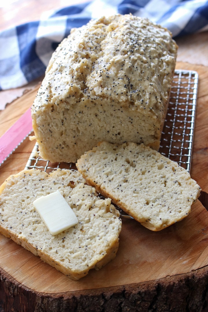 loaf of beer bread with 2 slices cut off. One slice with butter pat in middle