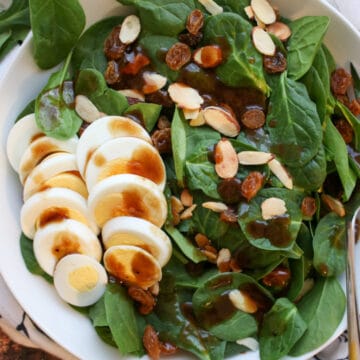 Spinach salad with sliced hard boiled eggs, nuts and raisins