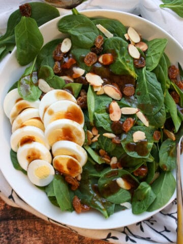 Spinach salad with sliced hard boiled eggs, nuts and raisins