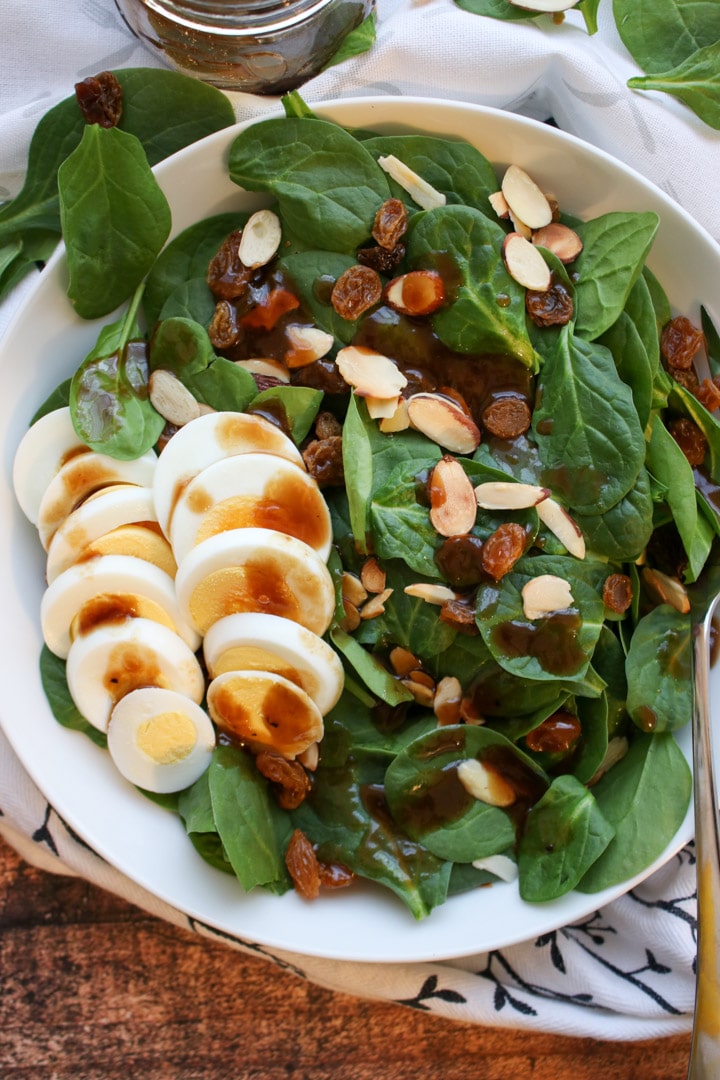 Spinach salad with sliced hard boiled eggs, nuts and raisins