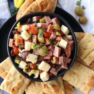 black bowl filled with dip and surrounded by crackers