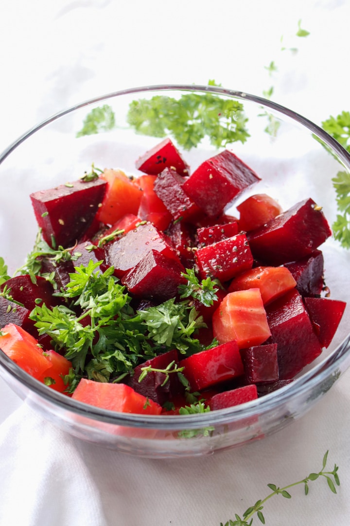 clear bowl with red beets and green herbs
