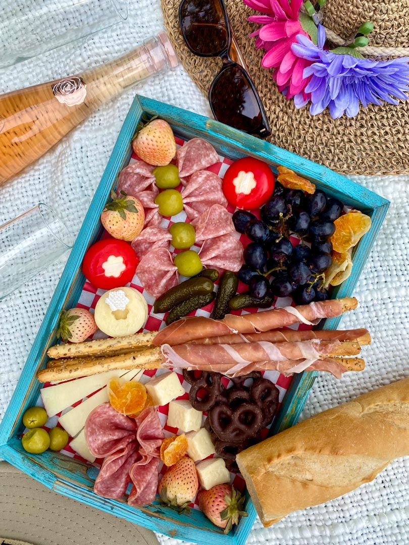 charcuterie board on a white blanket with a bottle of wine on the side