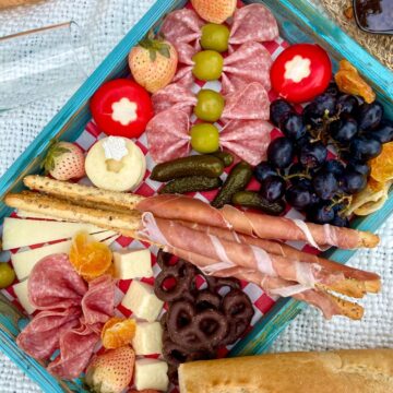 charcuterie board on a white blanket with a bottle of wine on the side