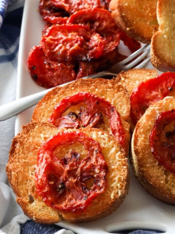 platter of roasted tomatoes on grill toast