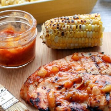 pork chop slathered in peach bbq sauce with corn on the cob