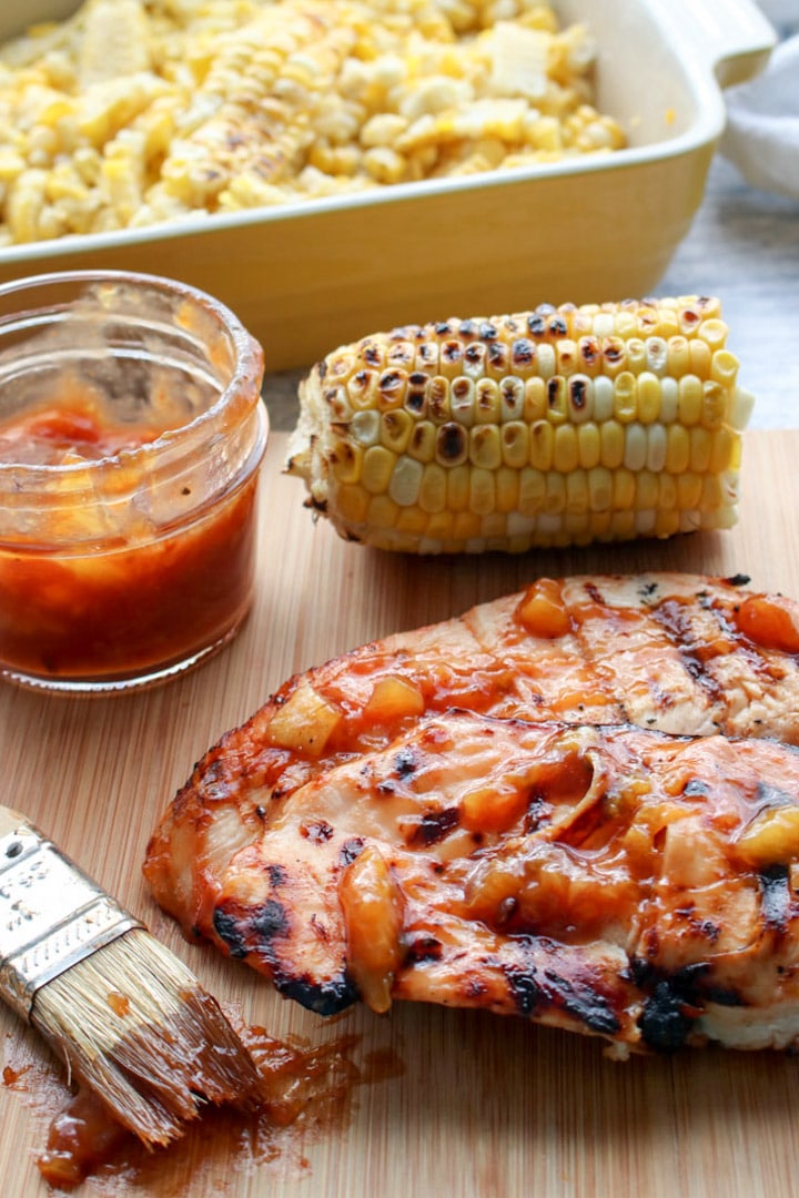 pork chop slathered in peach bbq sauce with corn on the cob