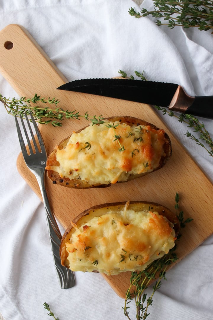 twice baked potato, steak on a cutting board. Glass of red wine on the side