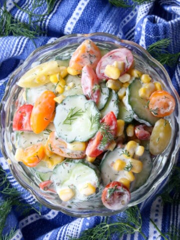 BOWL OF CREAMY CUCUMBER SALAD ON A BLUE AND WHITE TOWEL