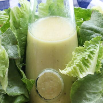 bottle of salad dressing sitting in a bowl of lettuce