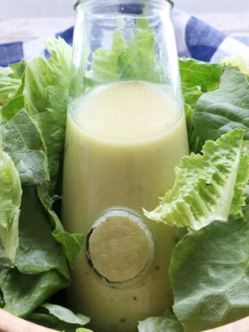 bottle of salad dressing sitting in a bowl of lettuce