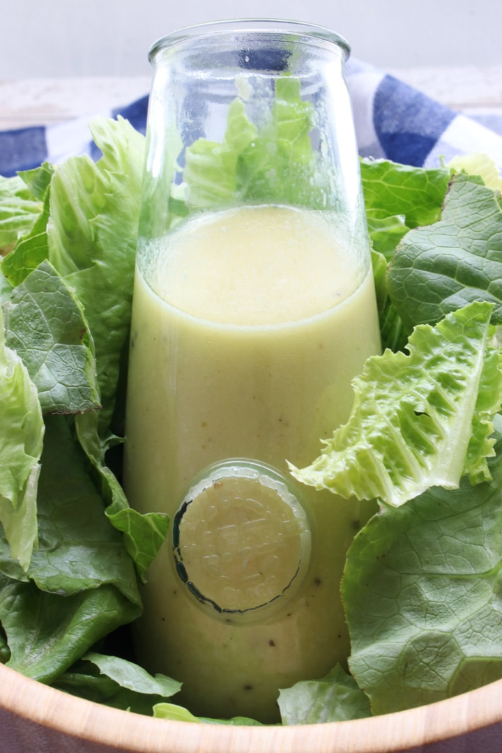 bottle of salad dressing sitting in a bowl of lettuce