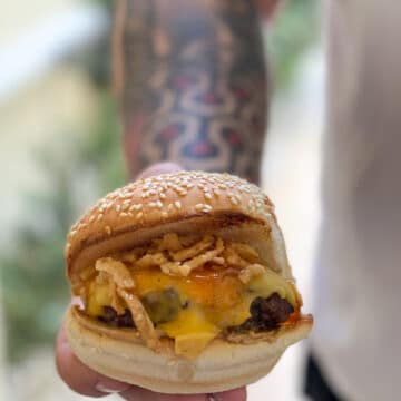 MAN WITH TATOO ON ARM HOLDING CHEESEBURGER