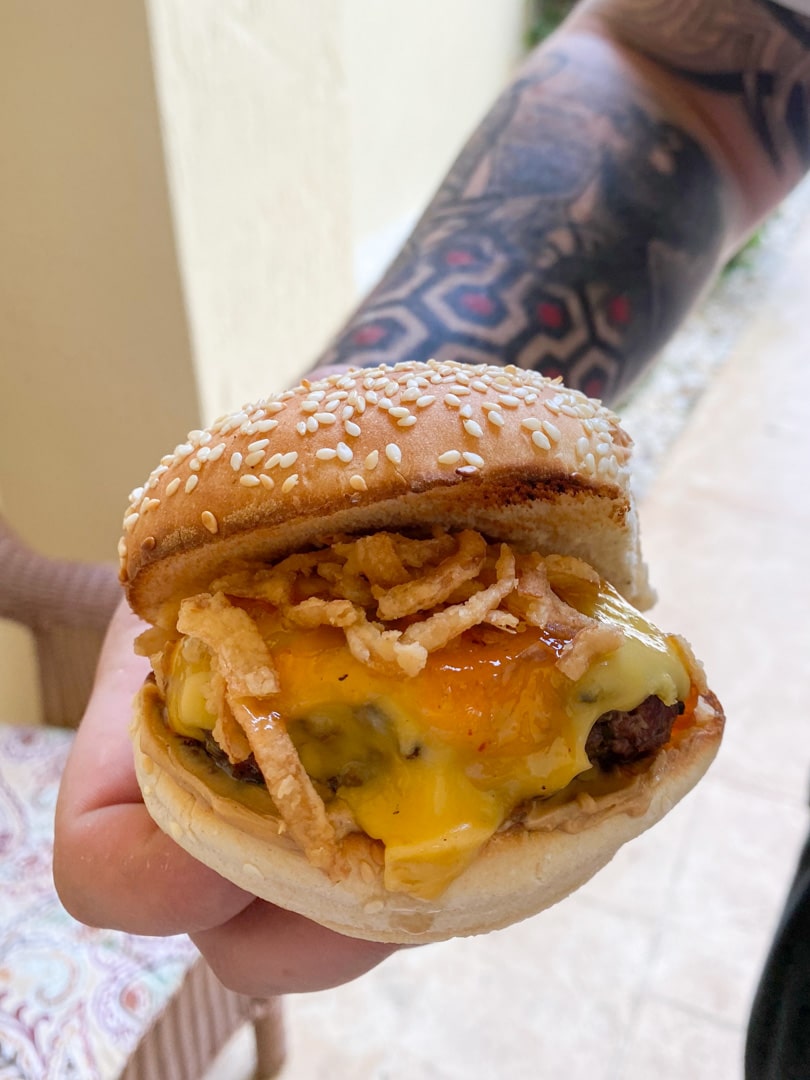 man's tattooed arm holding cheeseburger