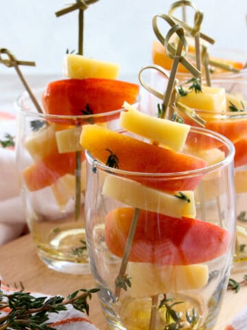 small appetizer glasses filled with peaches and gouda cheese on skewers