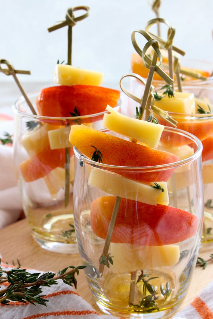 small appetizer glasses filled with peaches and gouda cheese on skewers