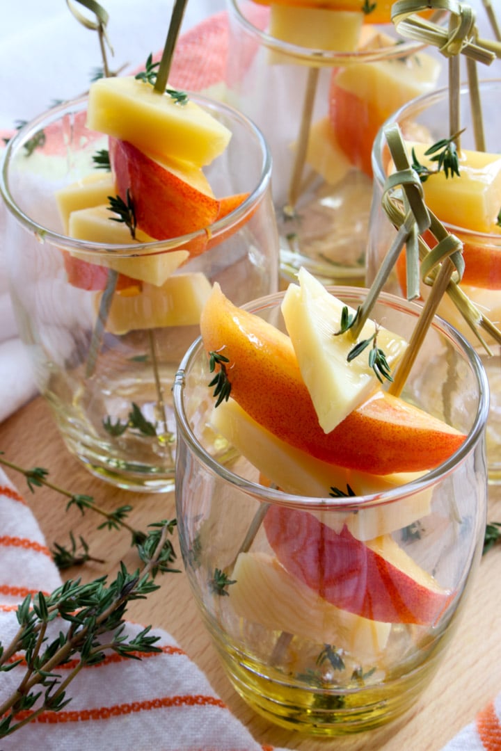 small appetizer glasses filled with peaches and gouda cheese on skewers