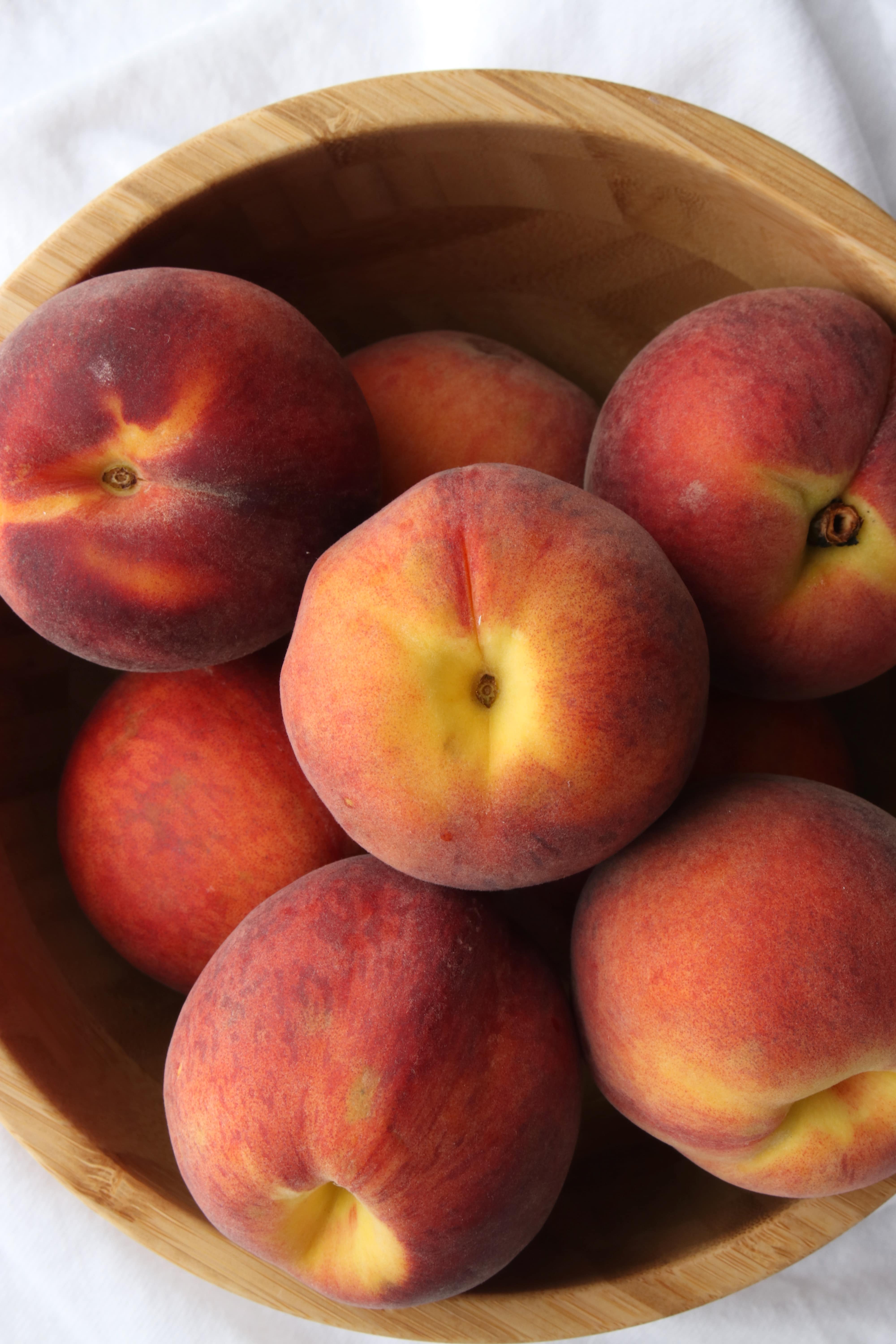 wooden bowl filled with peaches