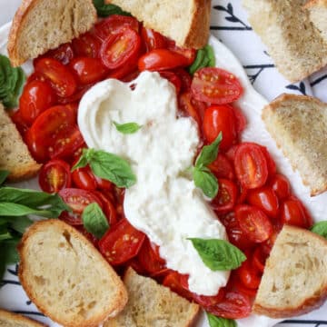 platter of roasted tomatoes, burrata cheese, toasted baguette slices, and fresh basil