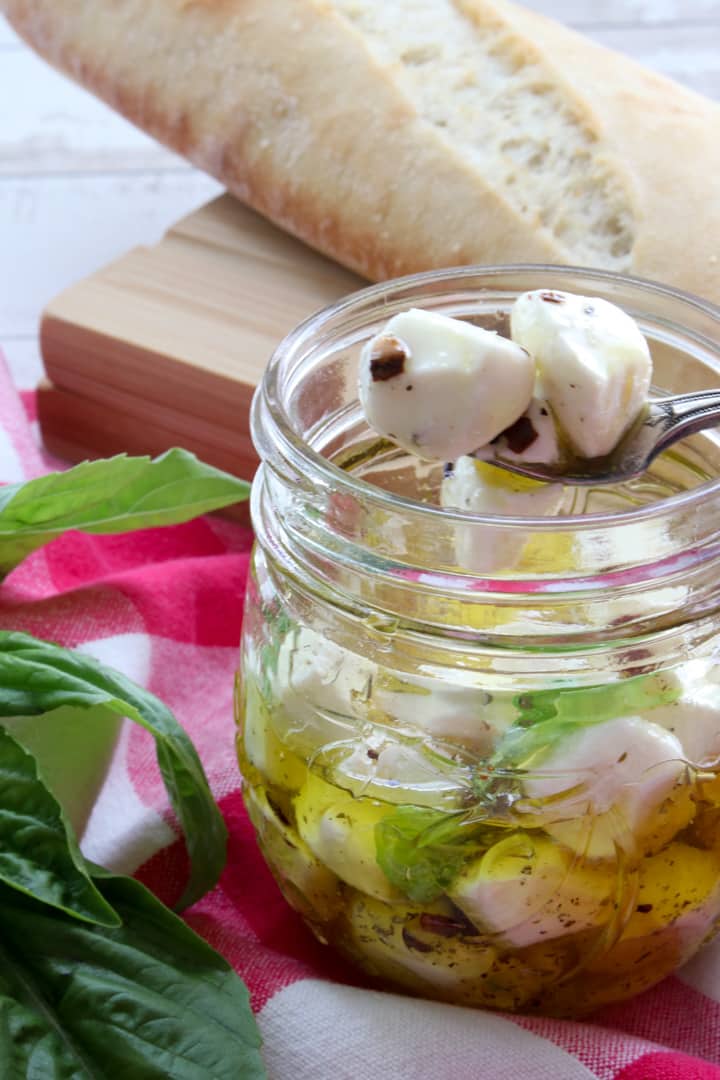 jar of marinated mozzarella balls with two on a fork