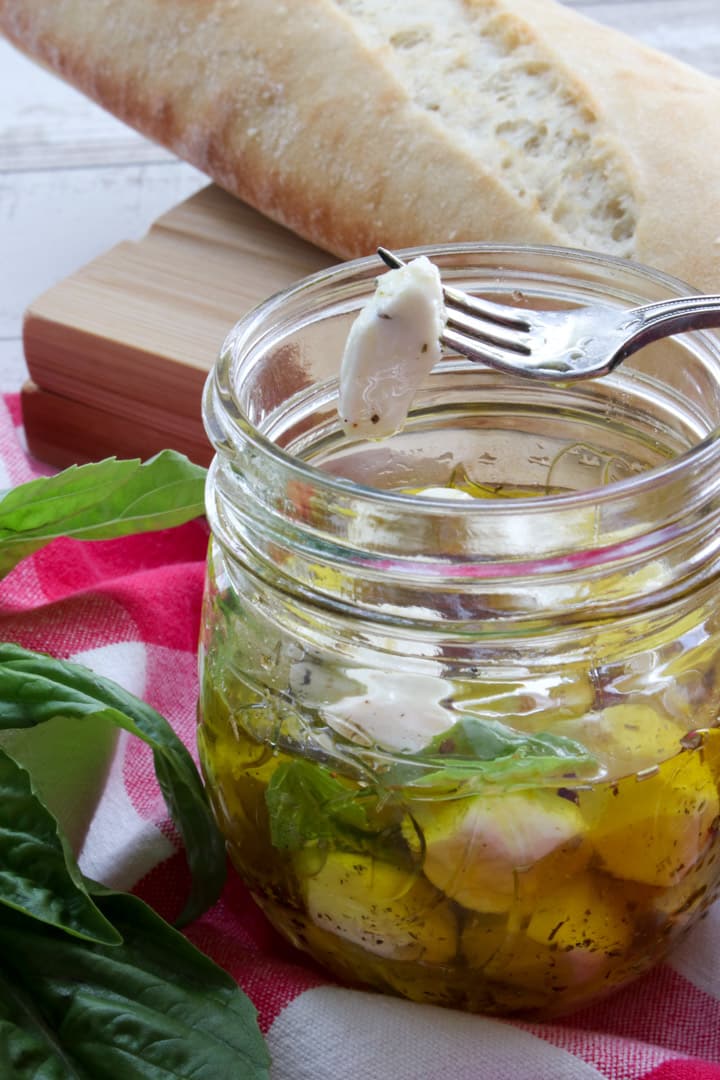 fork with one mozzarella pearl over the jar of mozzarella pearls