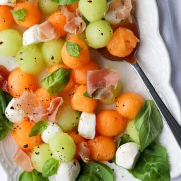 platter of melon ball prosciutto salad with mozzarella cheese and basil