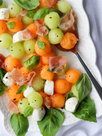 platter of melon ball prosciutto salad with mozzarella cheese and basil