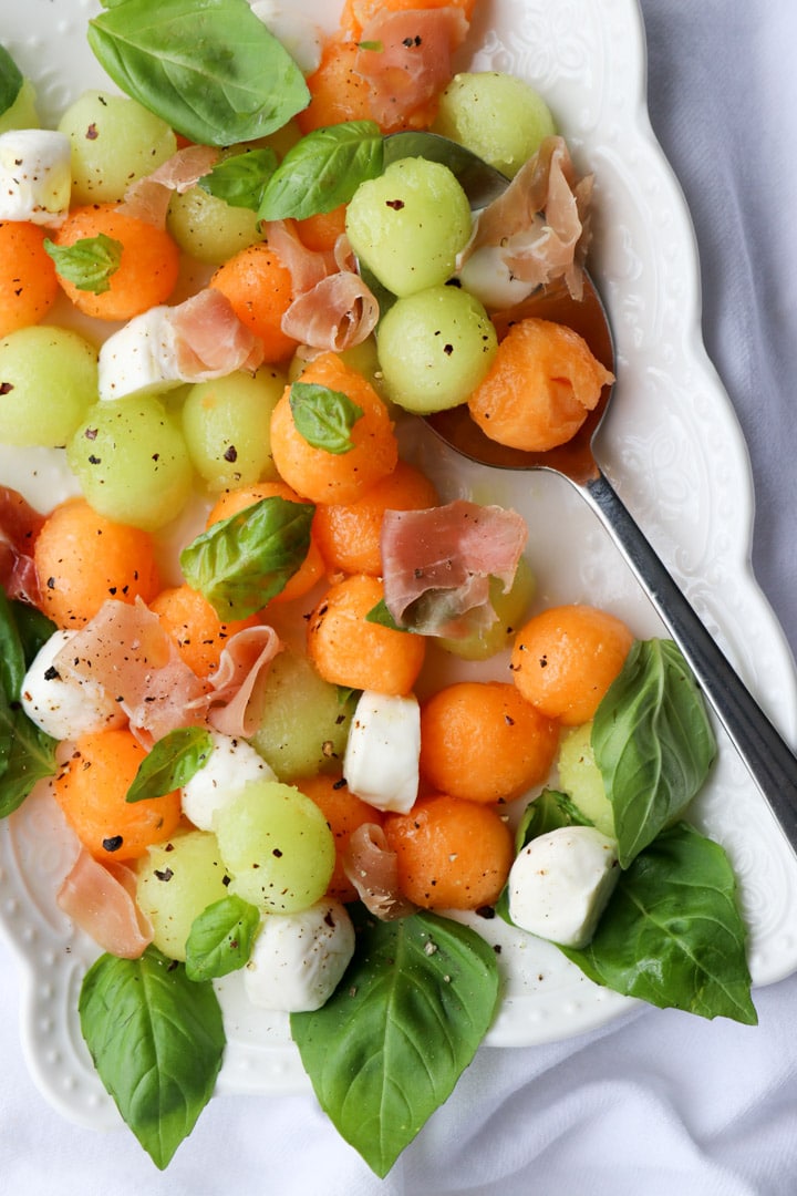 platter of melon ball prosciutto salad with mozzarella cheese and basil