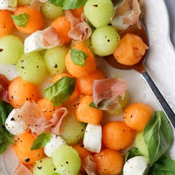 platter of melon ball prosciutto salad with mozzarella cheese and basil