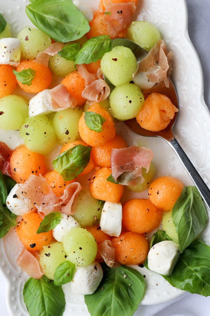platter of melon ball prosciutto salad with mozzarella cheese and basil