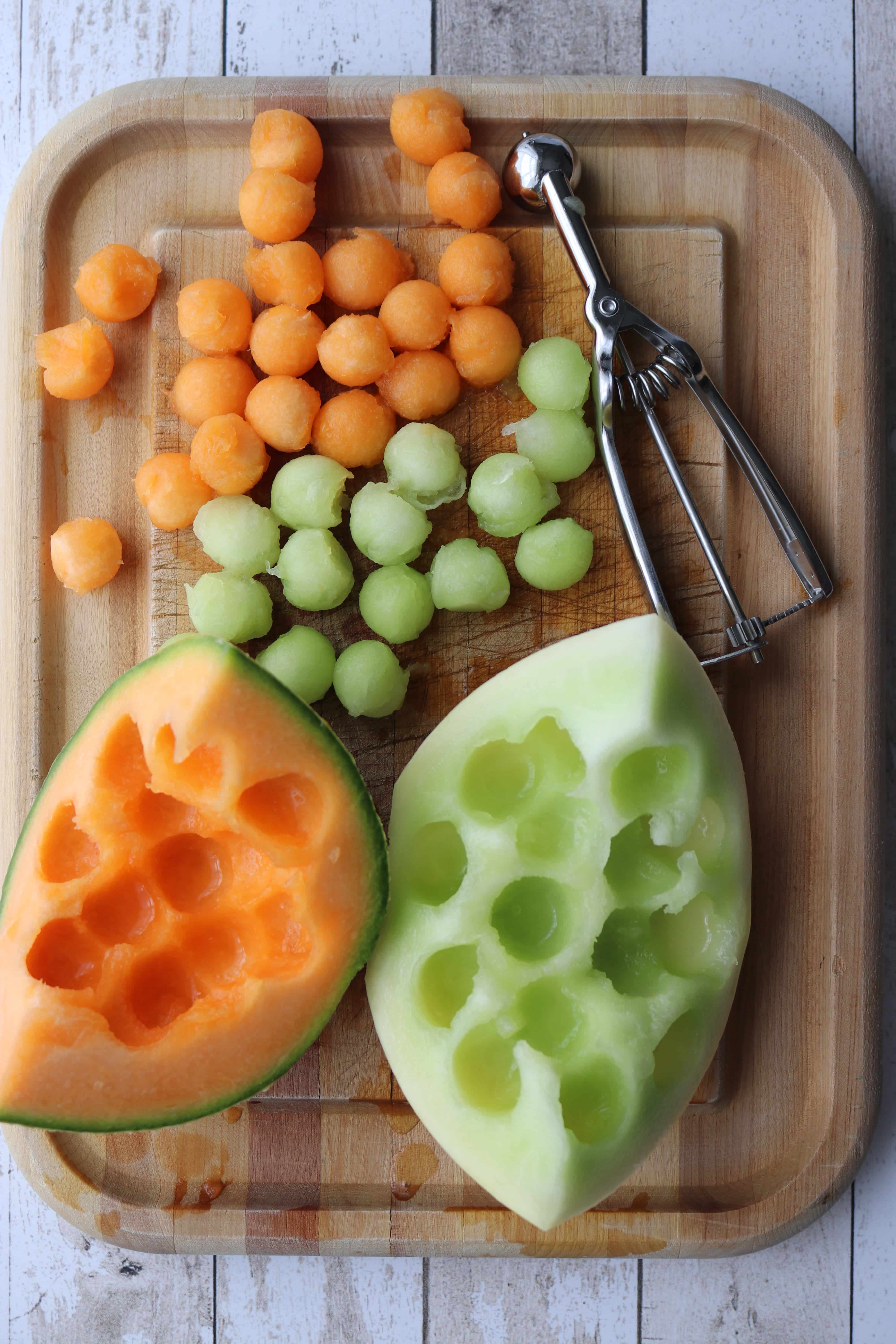 two quartered melons with ball sized piece cut out and placed on board