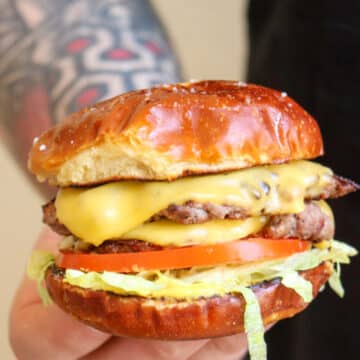 Man with tattooed arm holding cheeseburger