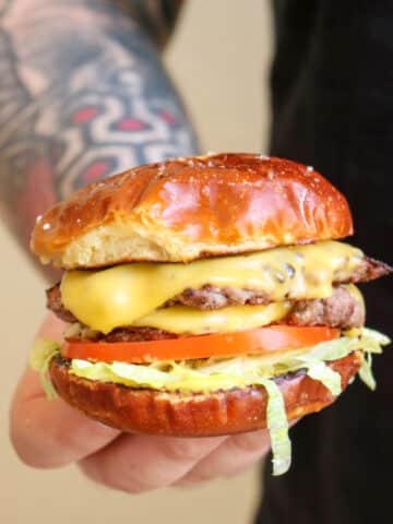 Man with tattooed arm holding cheeseburger