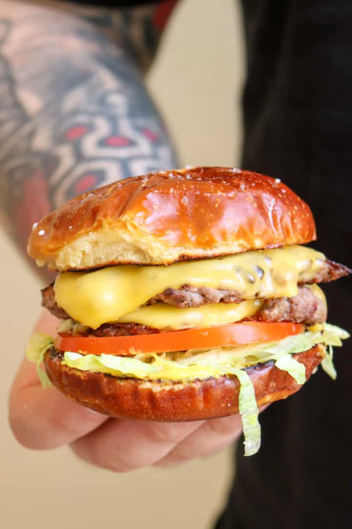 Man with tattooed arm holding cheeseburger