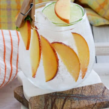 peach cocktail with glass line with sliced peaches and a mini clip