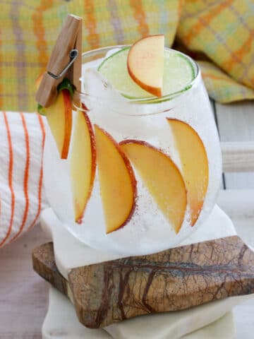 peach cocktail with glass line with sliced peaches and a mini clip