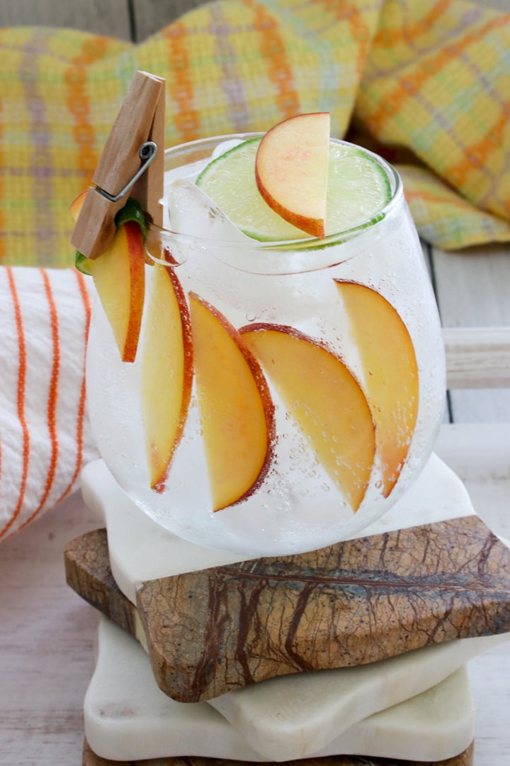 peach cocktail with glass line with sliced peaches and a mini clip