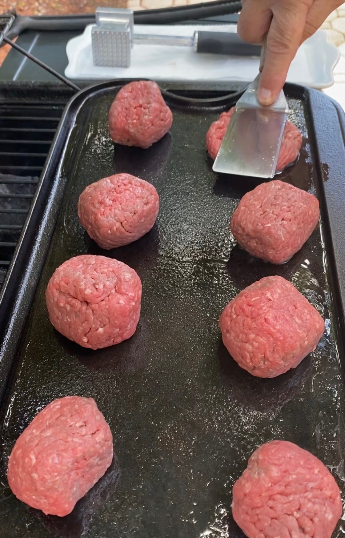 smashing round burger balls on a griddle