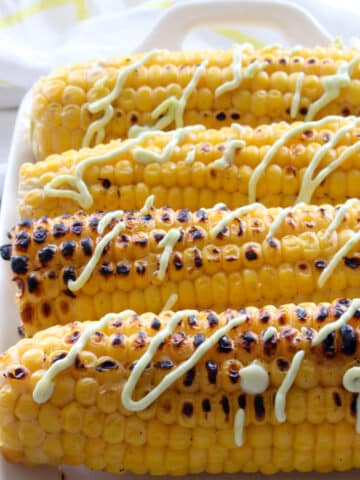 grilled corn on the cob with a drizzle of a avocado sauce