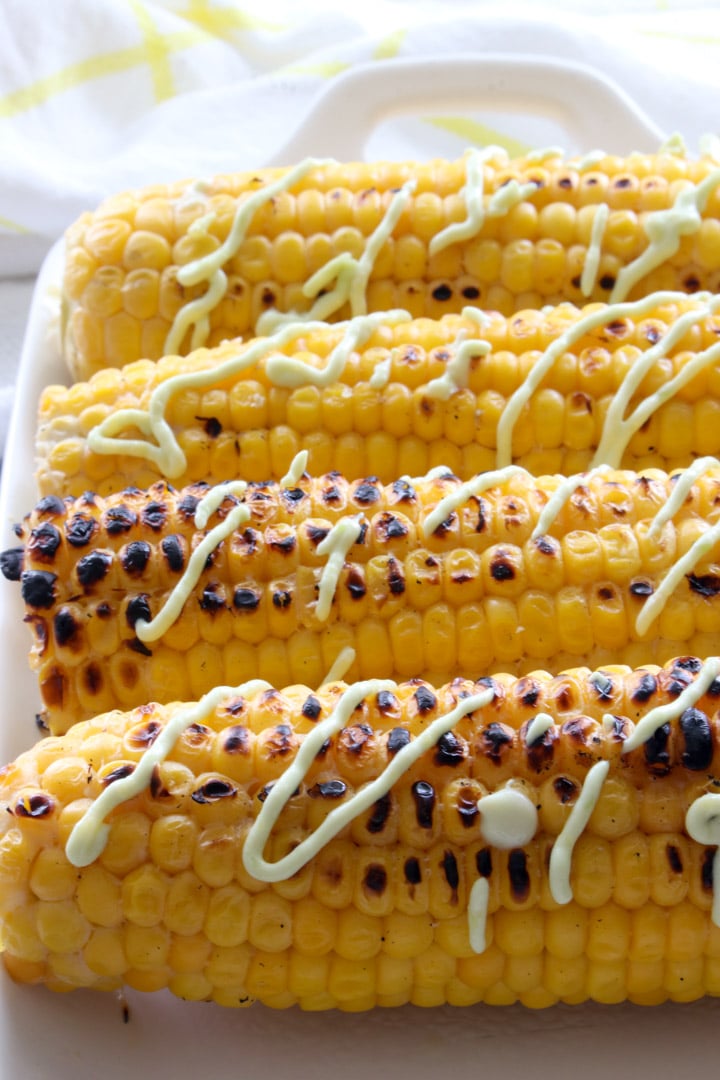 grilled corn on the cob with a drizzle of a avocado sauce