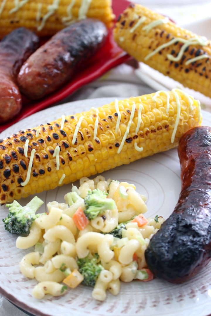 sausage, corn on the cob, and mac salad on a plate