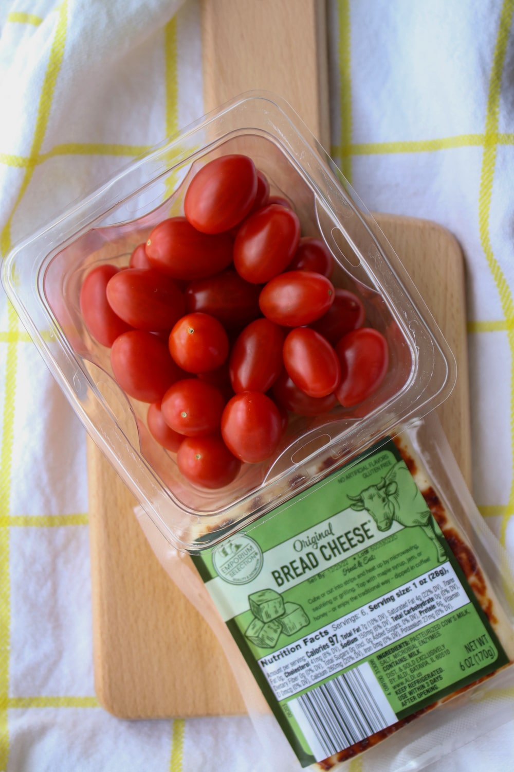 pint of cherry tomatoes and a package of bread cheese on a cutting board