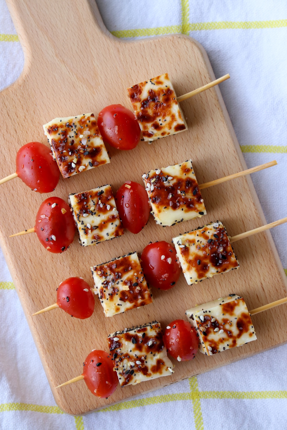 small board with 4 skewers of cherry tomatoes and cheese cubes.