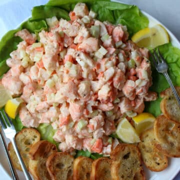 platter of shrimp salad with two lemons and toasted bread rounds