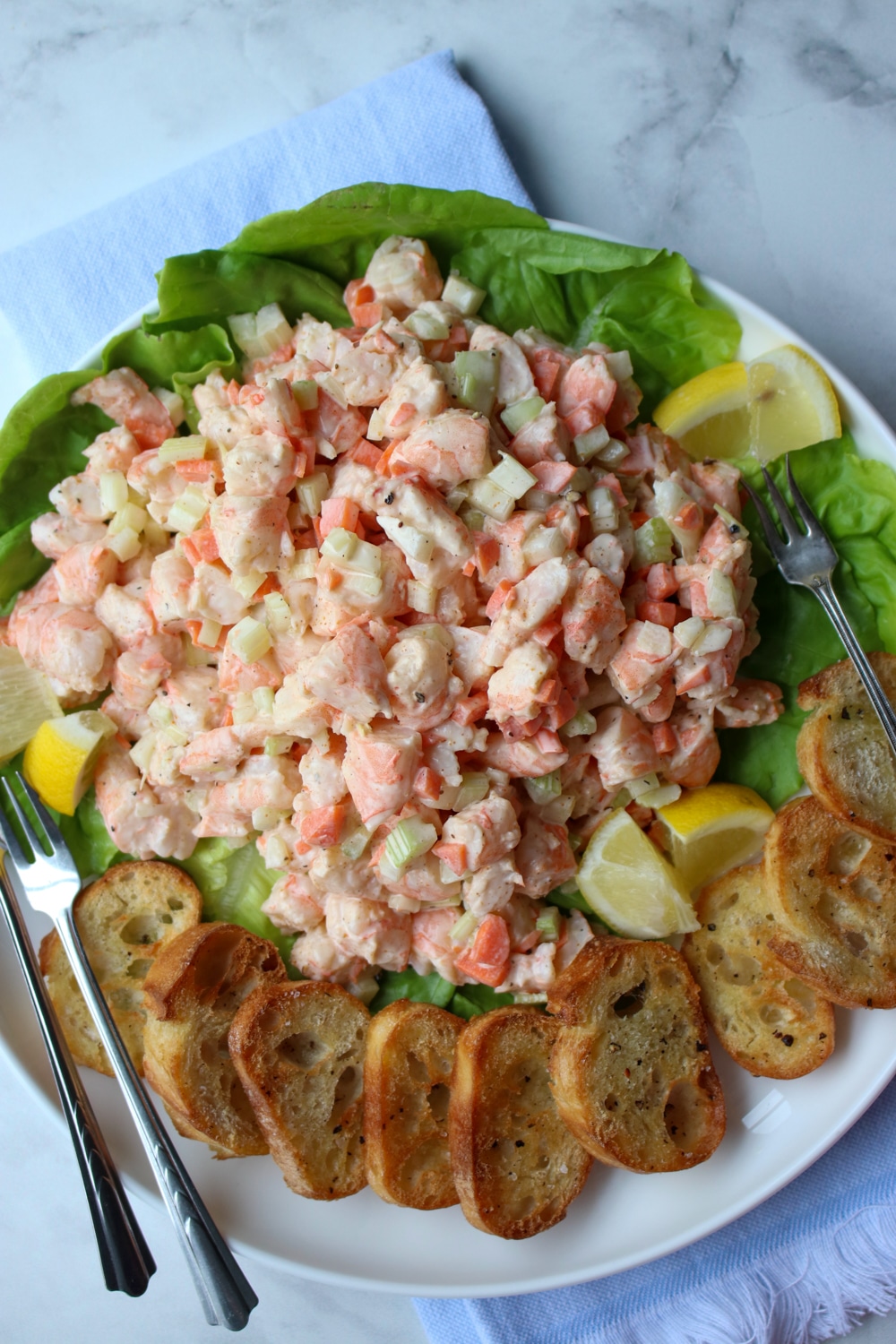 platter of shrimp salad with two lemons and toasted bread rounds