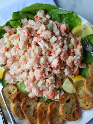 platter of shrimp salad with two lemons and toasted bread rounds