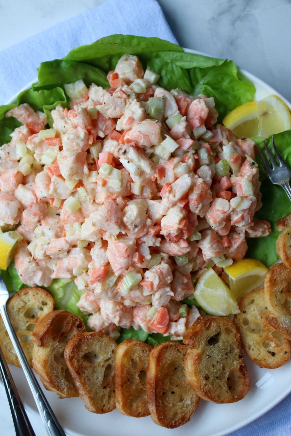 platter of shrimp salad with two lemons and toasted bread rounds